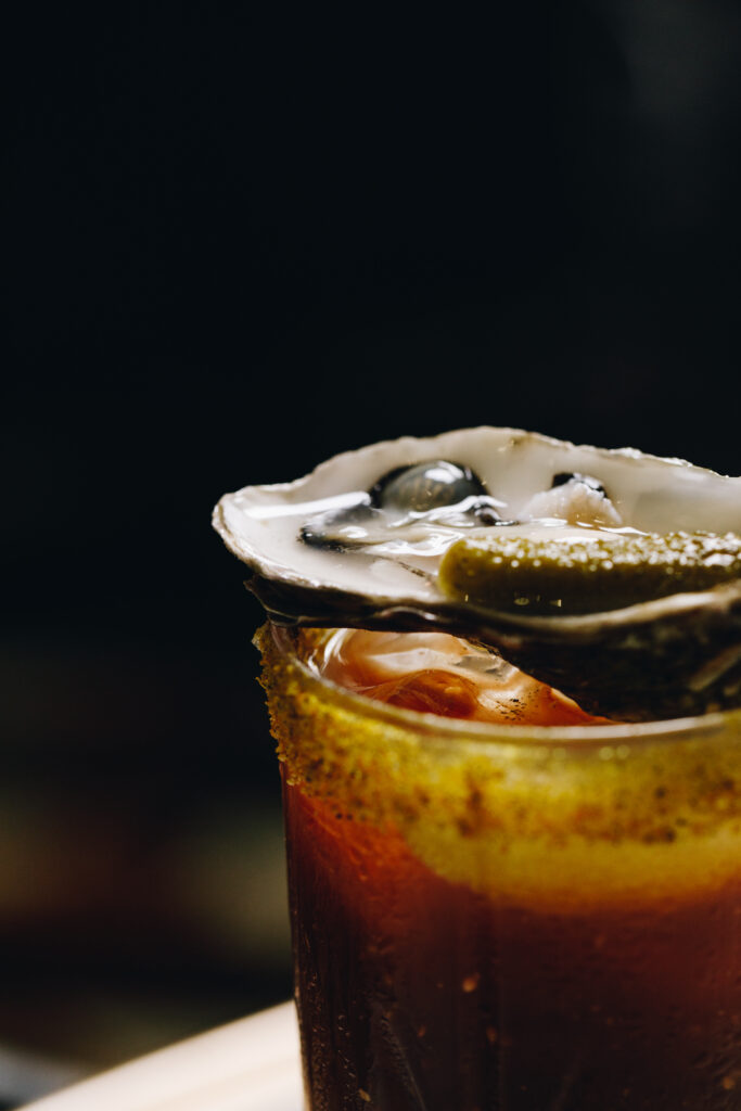 close up of oyster on top of drink 